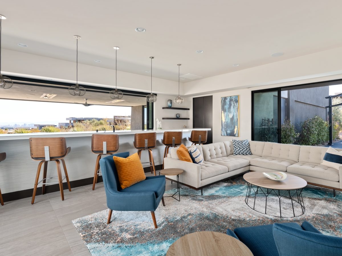 Casita living room and bar with tufted sectional, teal accents, and white quartz bar overlooking Las Vegas skyline, Reveal Interior Design Las Vegas