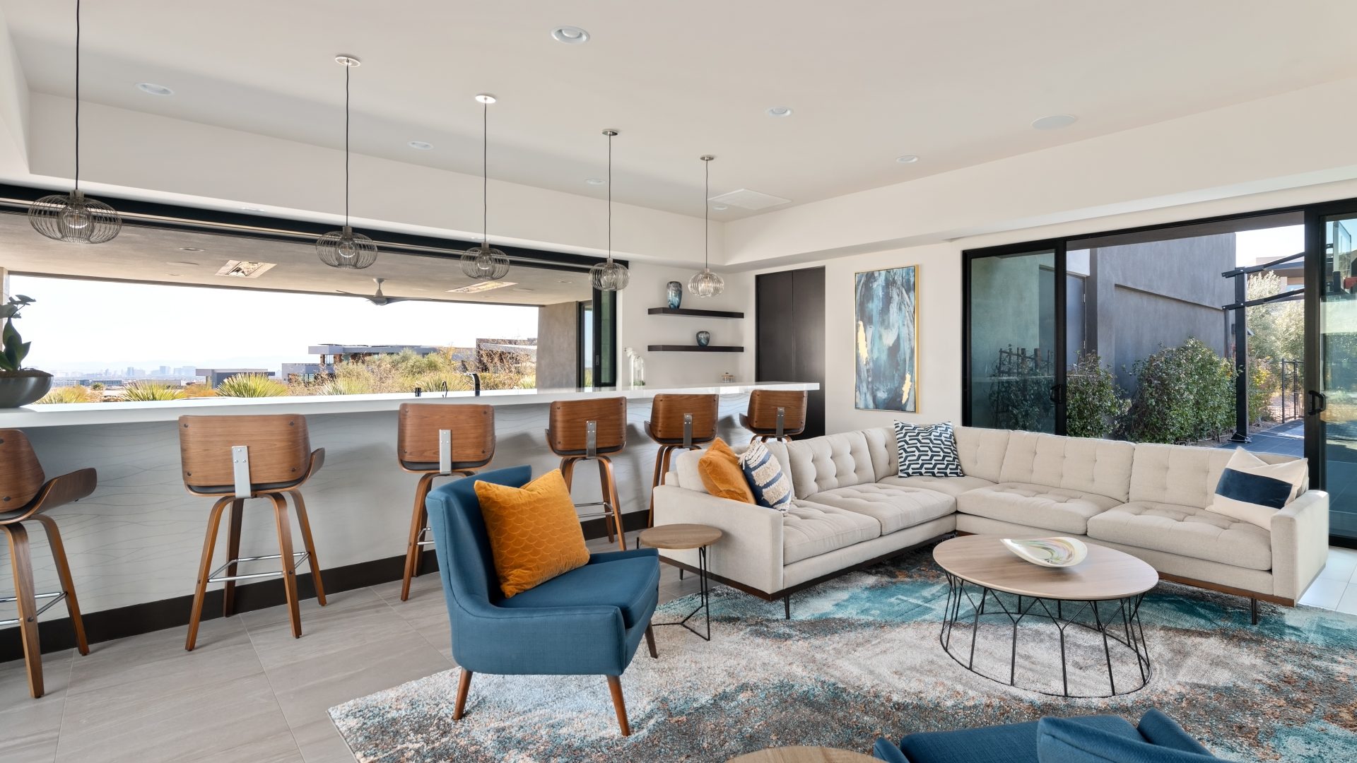 Casita living room and bar with tufted sectional, teal accents, and white quartz bar overlooking Las Vegas skyline, Reveal Interior Design Las Vegas
