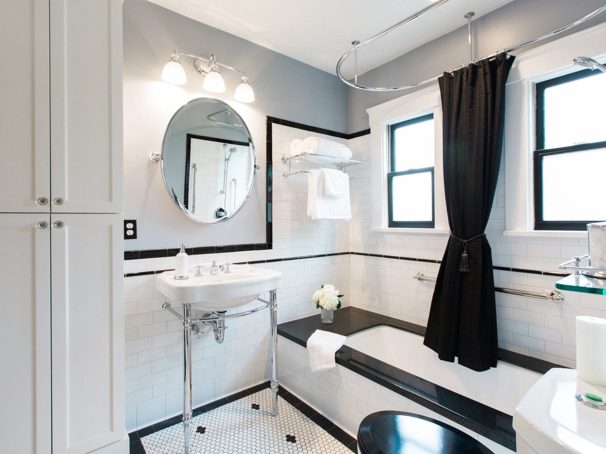 1920s-style black and white bathroom with hex mosaic floor, subway tile, and black granite tub surround, Reveal Interior Design Las Vegas