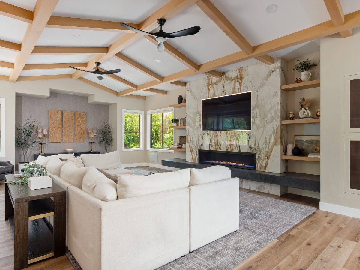 Living room with bookmatched porcelain fireplace surround, oak beam ceiling, and linear fireplace, Reveal Interior Design Las Vegas