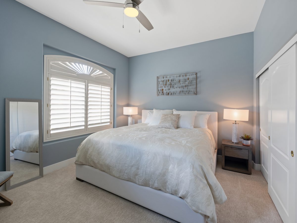 Primary bedroom with slate blue accent wall and tall upholstered headboard, Reveal Interior Design Las Vegas