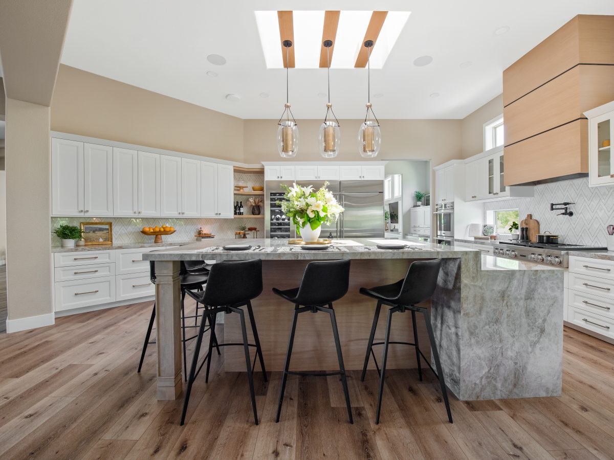 Transitional kitchen with Dekton Taj Mahal island, brushed brass accents, and custom wood hood, Reveal Interior Design Las Vegas