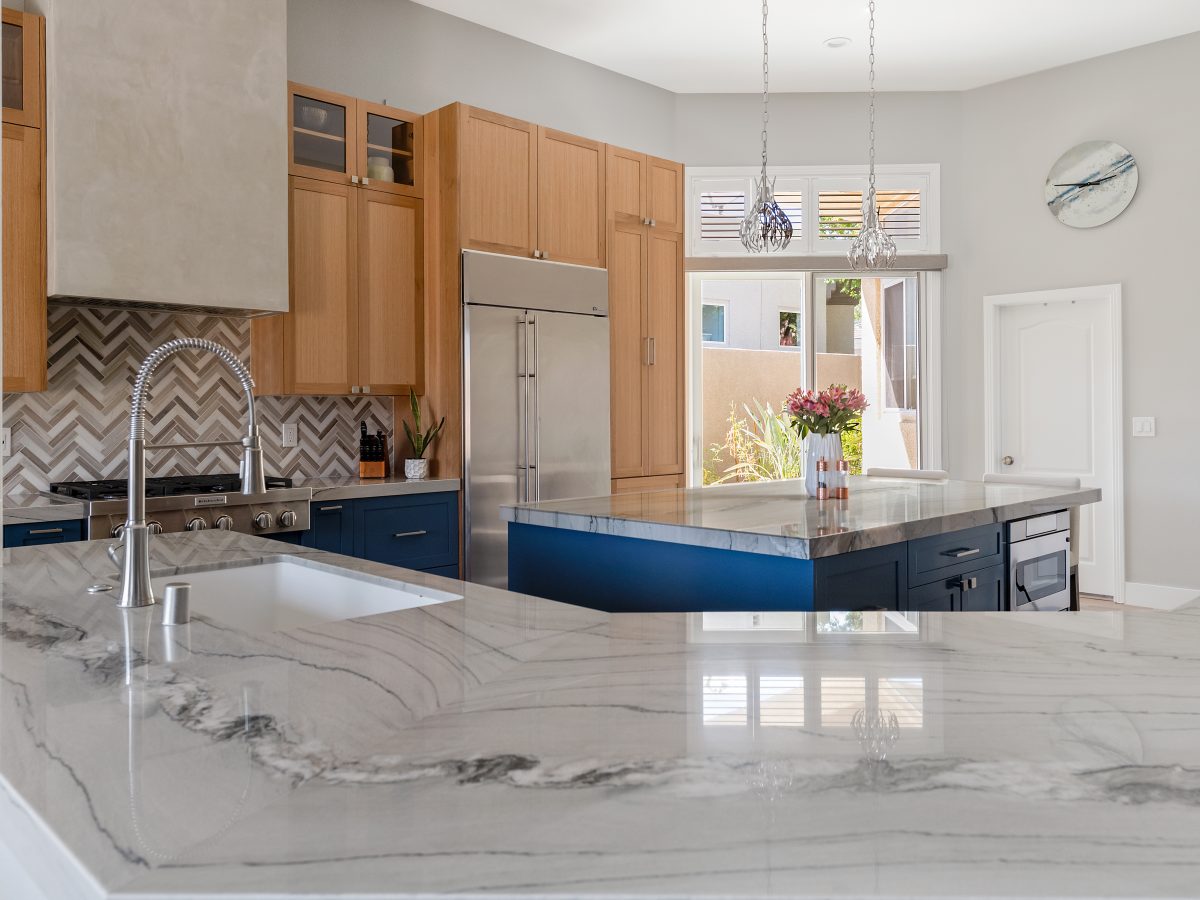 Luxury kitchen with quartzite countertops, dark blue and warm oak cabinetry, Reveal Interior Design Las Vegas