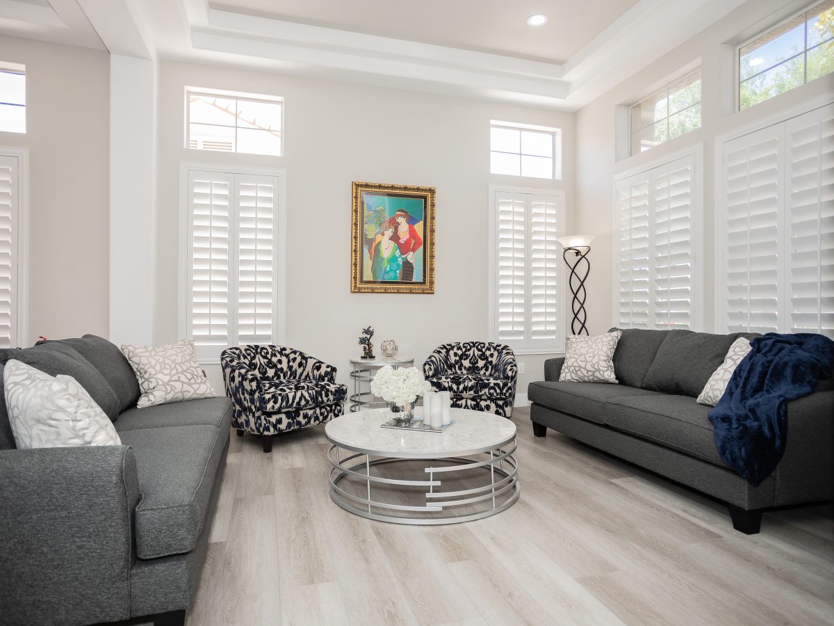 Living room with gray sofas, stone-look round coffee table, and patterned accent chairs, Reveal Interior Design Las Vegas