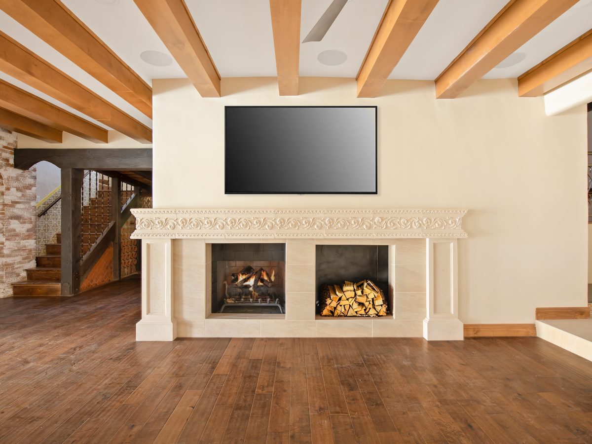 Living room with custom cast travertine-style fireplace surround, wood storage, and wall-mounted TV, Reveal Interior Design Las Vegas