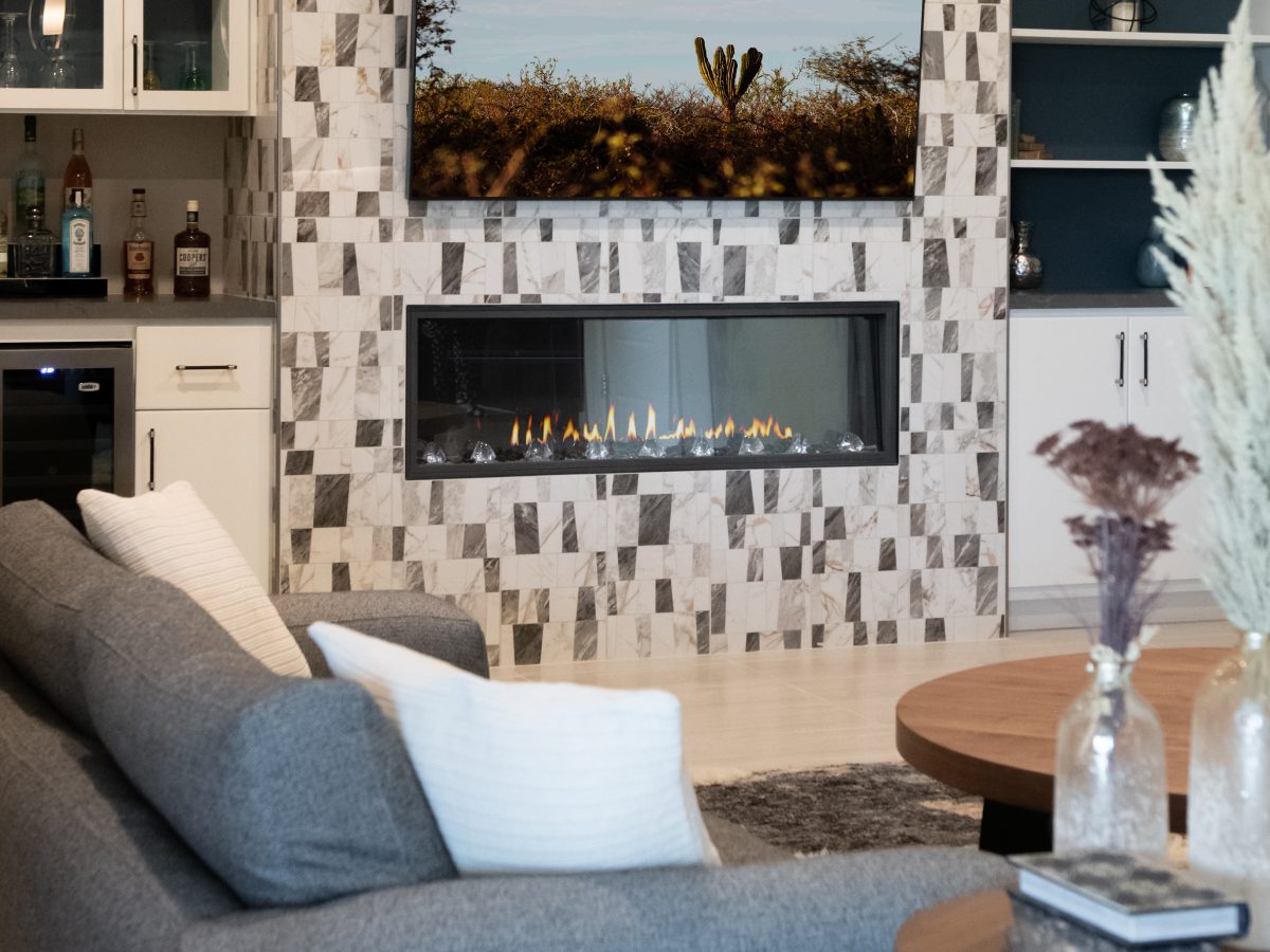 Living room linear fireplace wall with polished porcelain tile, built-in bar, and mounted TV, Reveal Interior Design Las Vegas