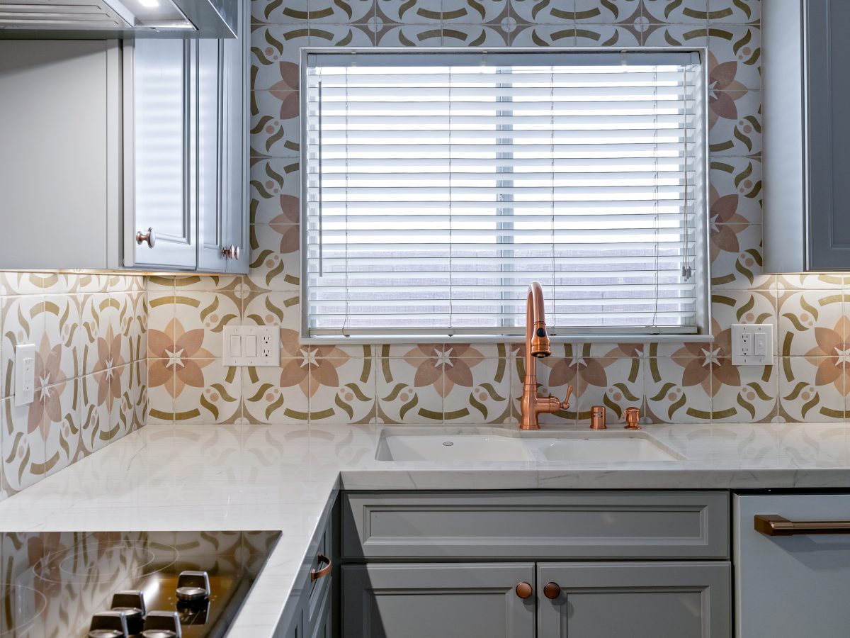 Kitchen with encaustic ceramic tile backsplash, white quartz countertops, and copper fixtures, Reveal Interior Design Las Vegas