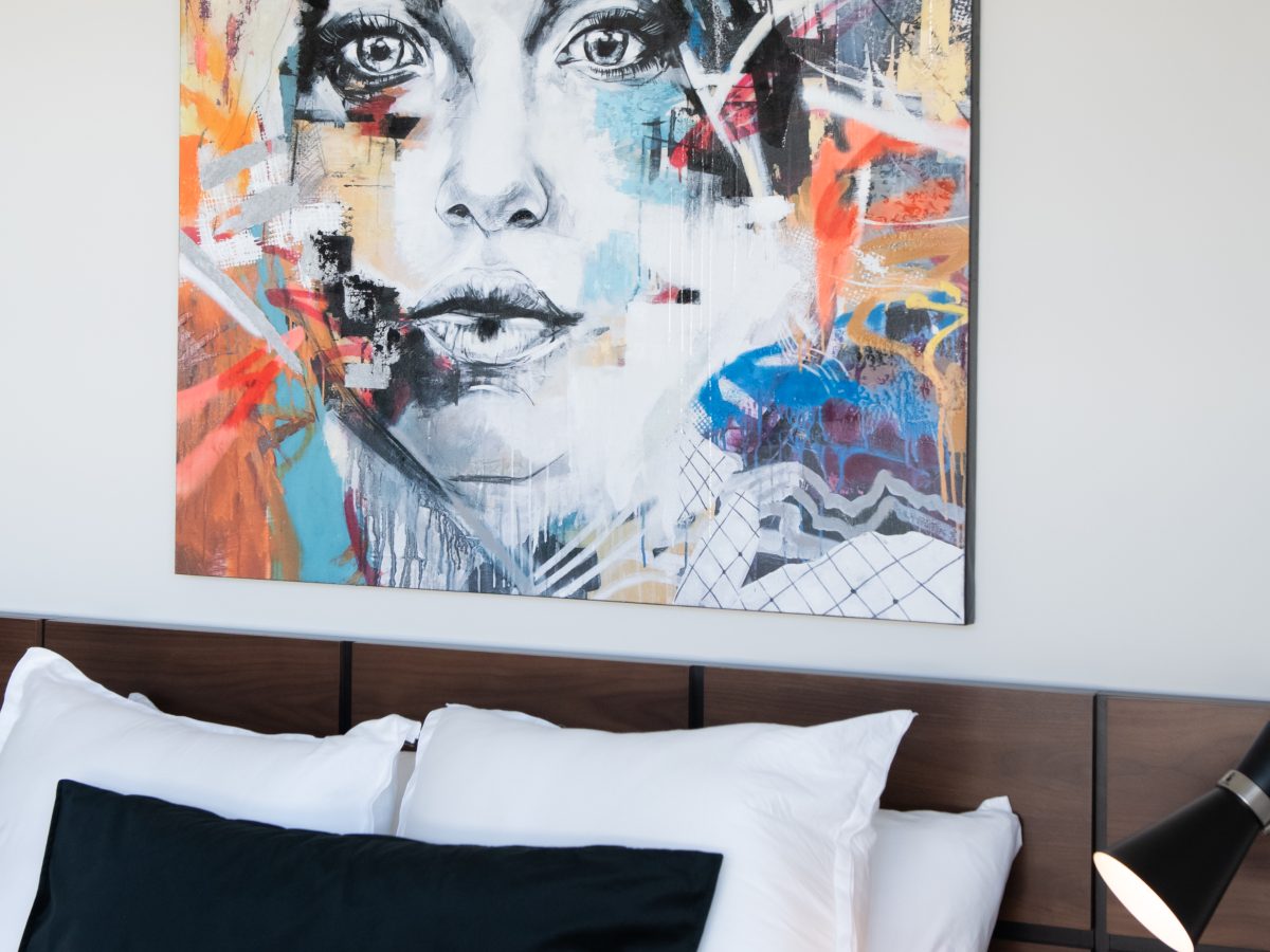 Secondary bedroom with bold abstract portrait artwork above walnut headboard, Reveal Interior Design Las Vegas
