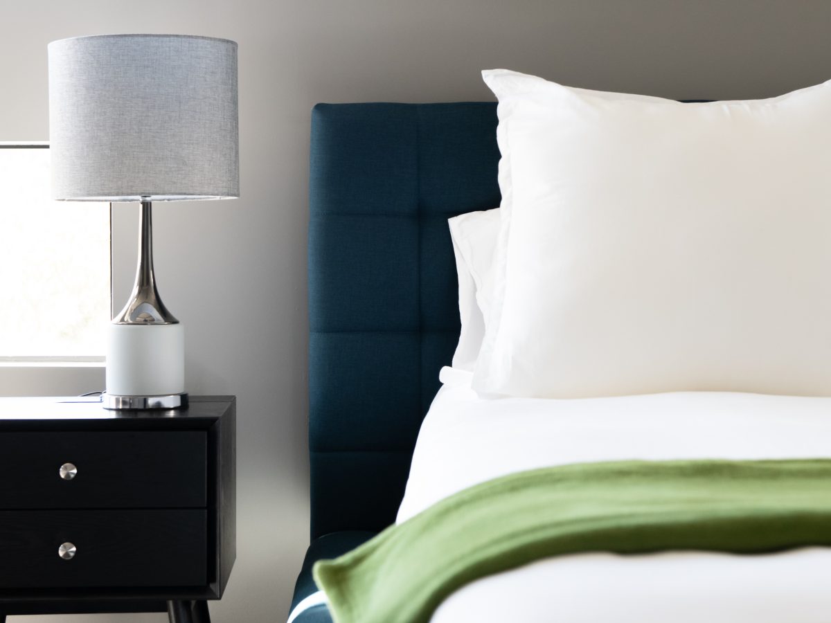 Contemporary secondary bedroom with teal upholstered headboard and green accent throw, Reveal Interior Design Las Vegas