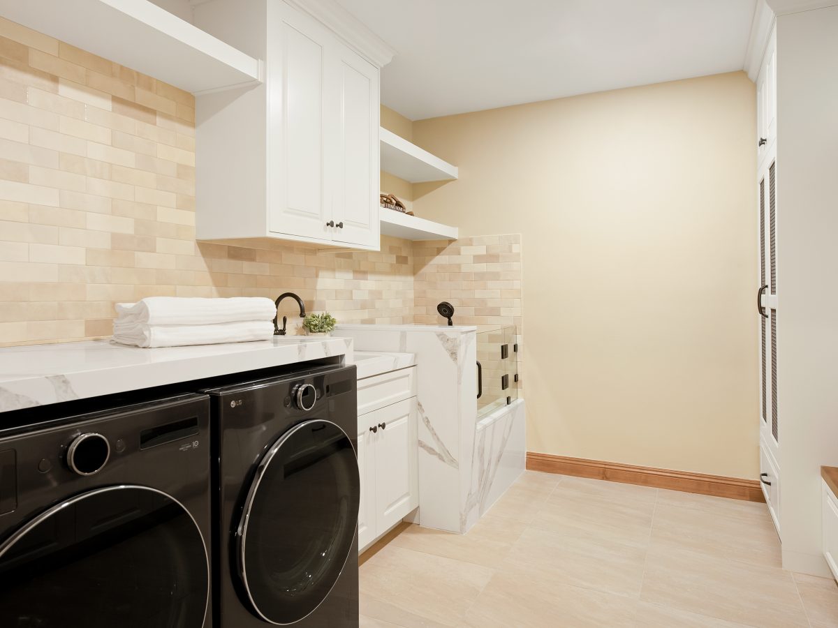Modern Spanish laundry room with marble-veined quartz counters and black stainless appliances, Reveal Interior Design Las Vegas