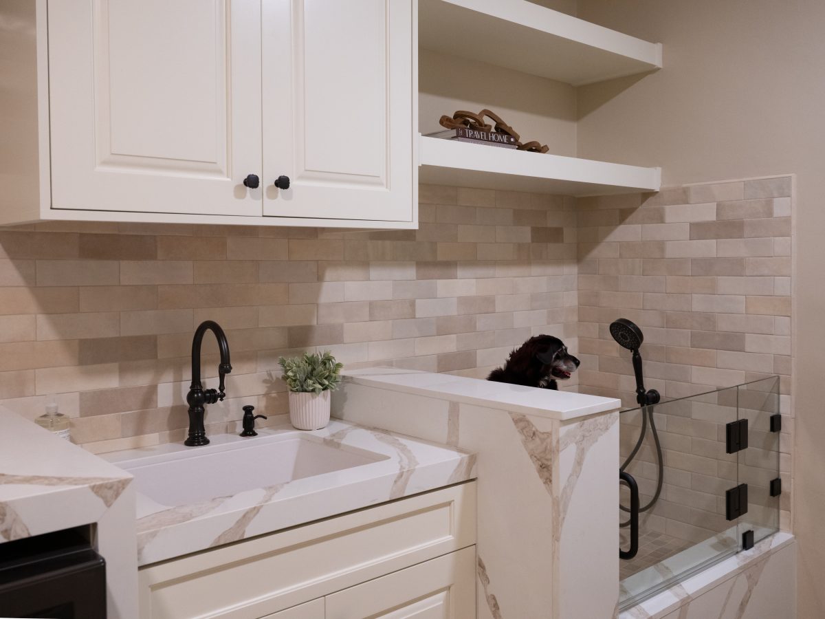 Modern Spanish laundry room with dog wash station, white quartz sink surround, and cream cabinetry, Reveal Interior Design Las Vegas