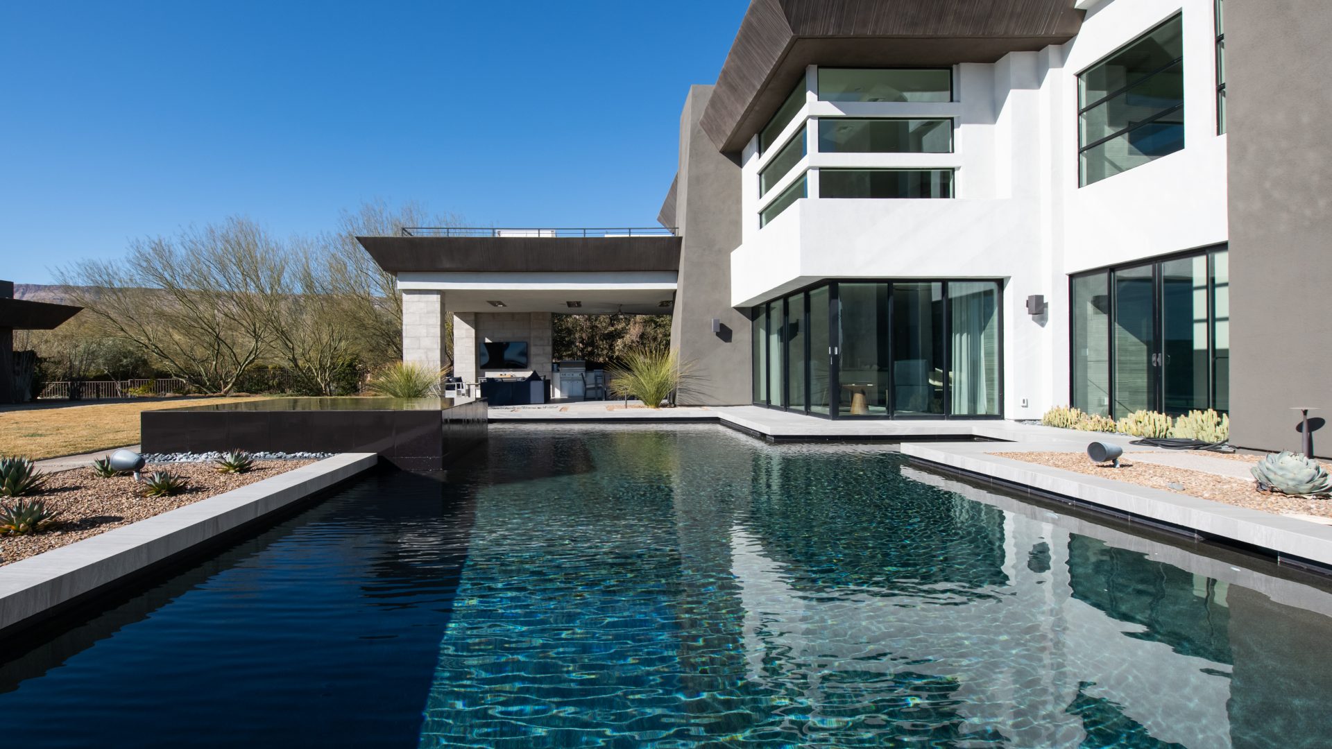 Desert Modern backyard with lap pool, casita bar seating, and Las Vegas Strip views, Reveal Interior Design Las Vegas