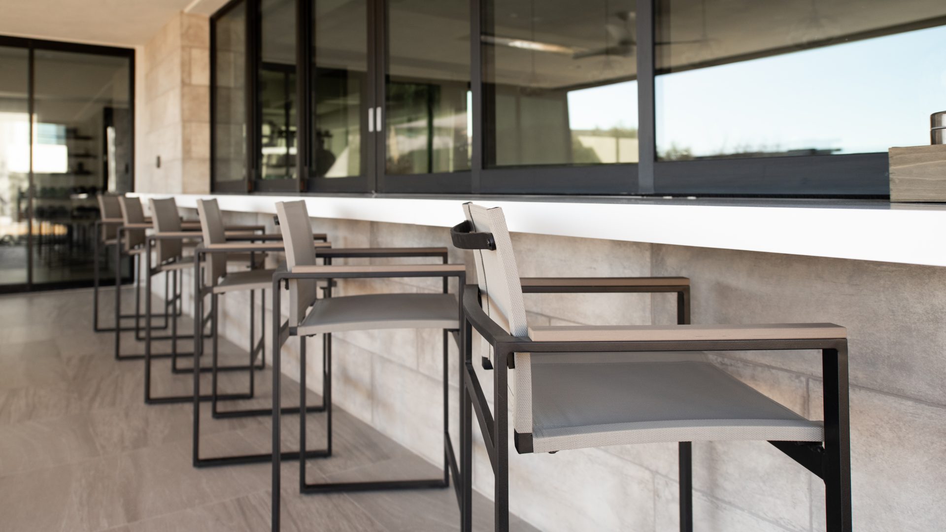 Outdoor bar seating with modern metal stools at covered casita counter, Reveal Interior Design Las Vegas