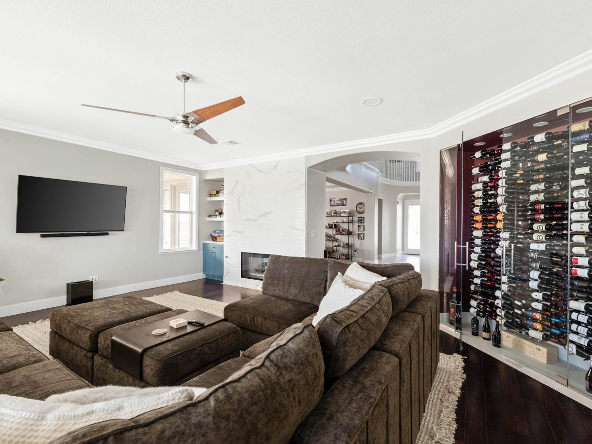 Living room with custom built-in wine storage and dimensional porcelain tile fireplace surround, Reveal Interior Design Las Vegas
