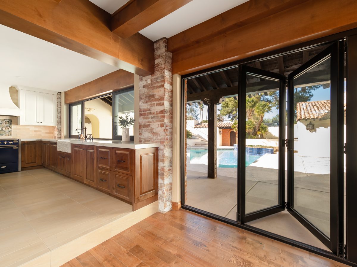 Spanish Modern kitchen with blue quartzite island, maple cabinetry, and folding glass doors to pool, Reveal Interior Design Las Vegas