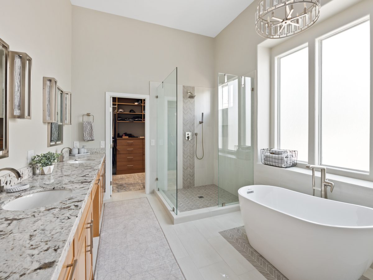 Primary bathroom with granite dual vanity, freestanding soaking tub, and glass walk-in shower, Reveal Interior Design Las Vegas