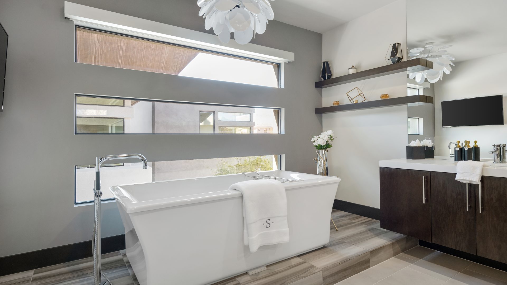 Primary bathroom with freestanding soaking tub, marble-look porcelain slab, and petal chandelier, Reveal Interior Design Las Vegas