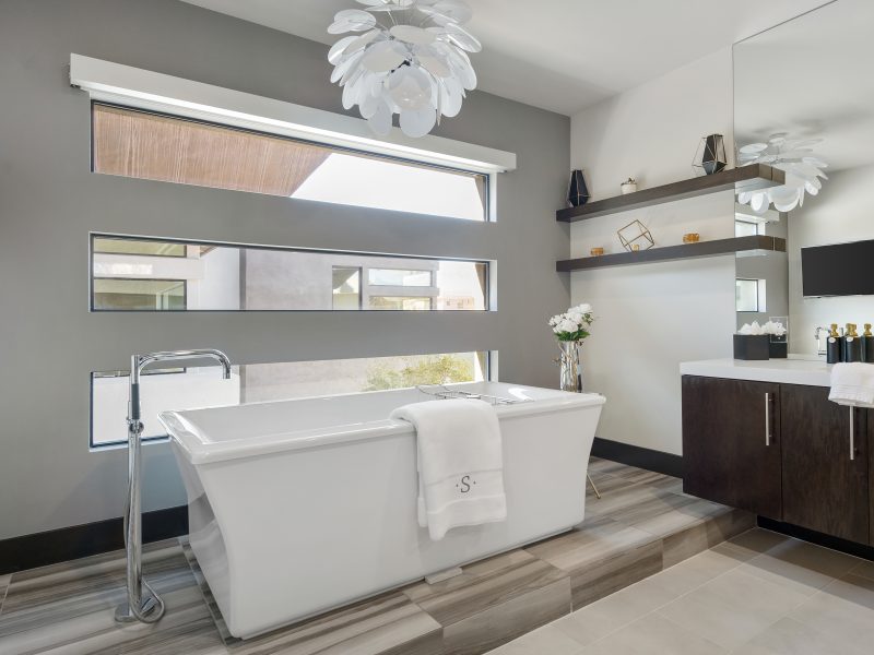 Primary bathroom with freestanding soaking tub, marble-look porcelain slab, and petal chandelier, Reveal Interior Design Las Vegas