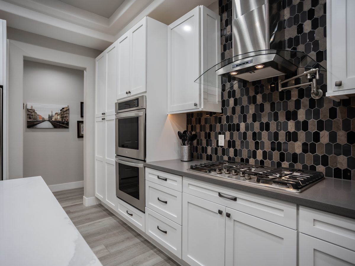 Contemporary kitchen with white shaker cabinets, elongated hex mosaic backsplash, and stainless steel appliances, Reveal Interior Design Las Vegas