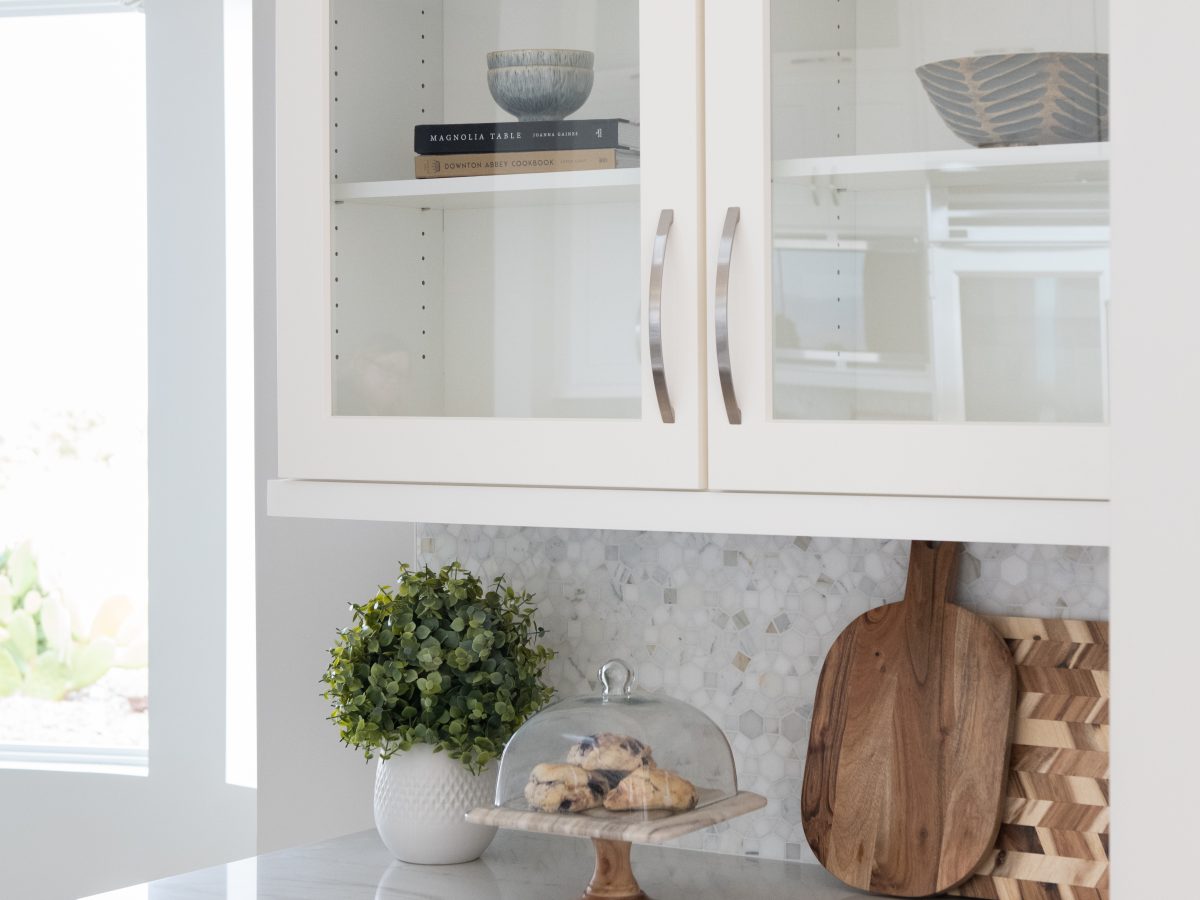 Transitional kitchen butler's pantry with Taj Mahal quartzite countertops and glass-front white cabinetry, Reveal Interior Design Las Vegas