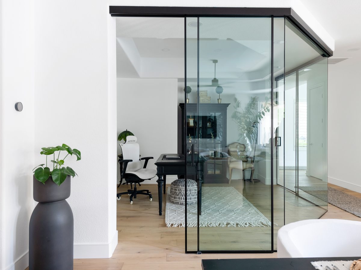 Home office with black metal and clear glass wall enclosure, warm oak engineered flooring, Reveal Interior Design Las Vegas