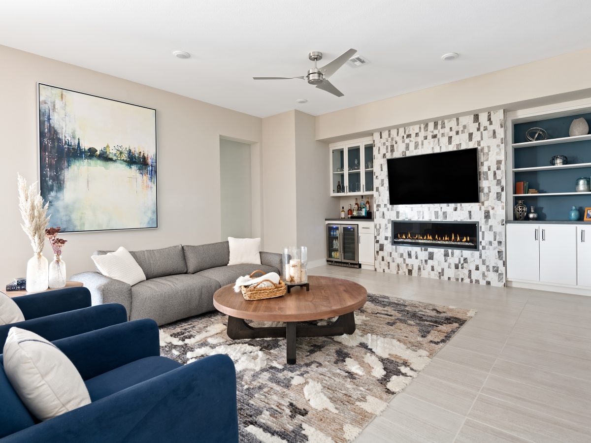 Contemporary living room with linear fireplace, built-in bar, and custom teal-backed cabinetry, Reveal Interior Design Las Vegas