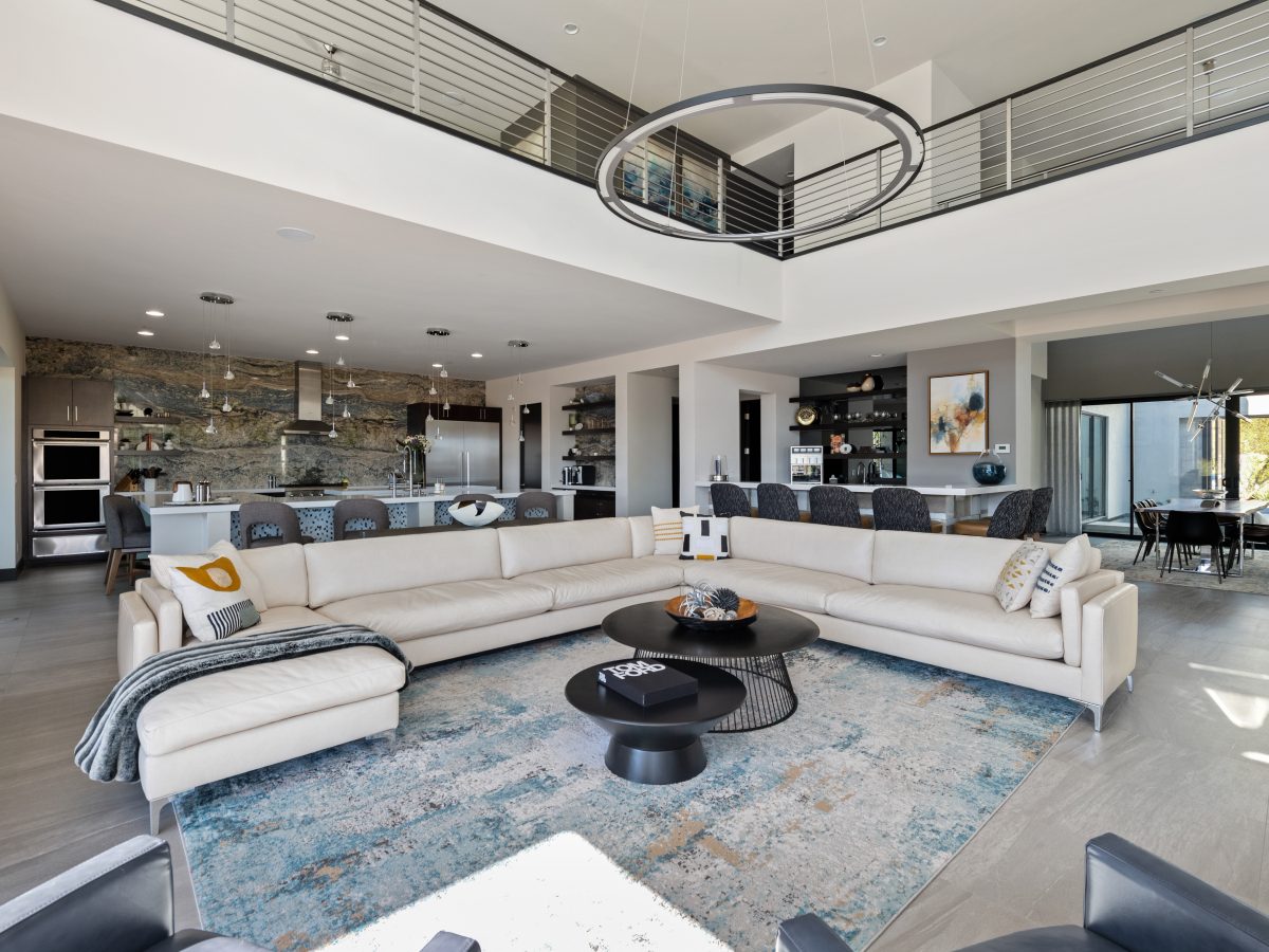 Double-height open-plan living room with custom sectional sofa and ring LED pendant, Reveal Interior Design Las Vegas