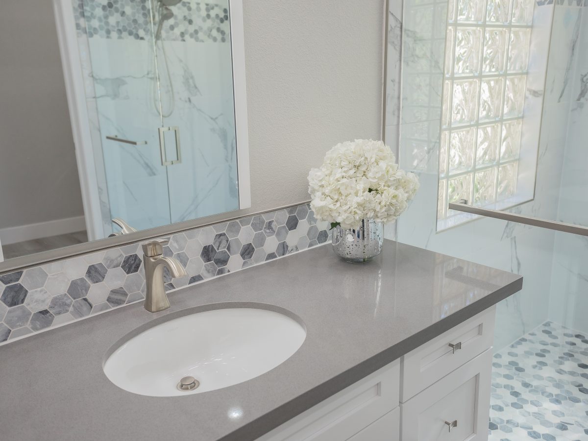 Primary bathroom with greige quartz vanity, hexagon mosaic backsplash, and marble-look porcelain shower, Reveal Interior Design Las Vegas