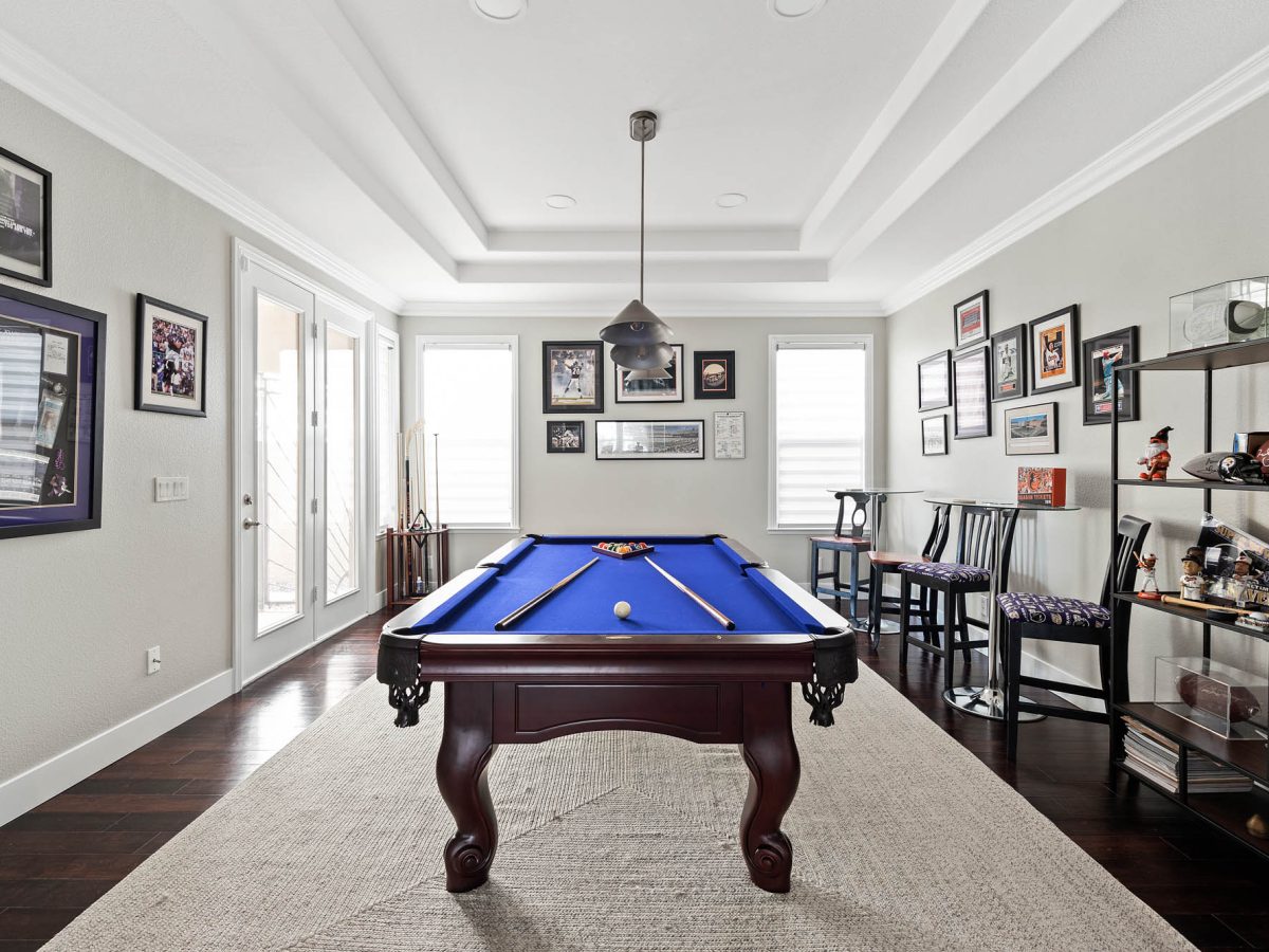 Sports-themed game room with blue billiard table and cherry wood flooring, Reveal Interior Design Las Vegas