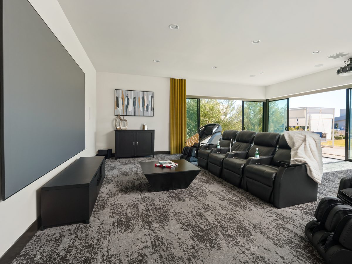Home theater with leather recliners, gold draperies, and expansive movie screen, Reveal Interior Design Las Vegas