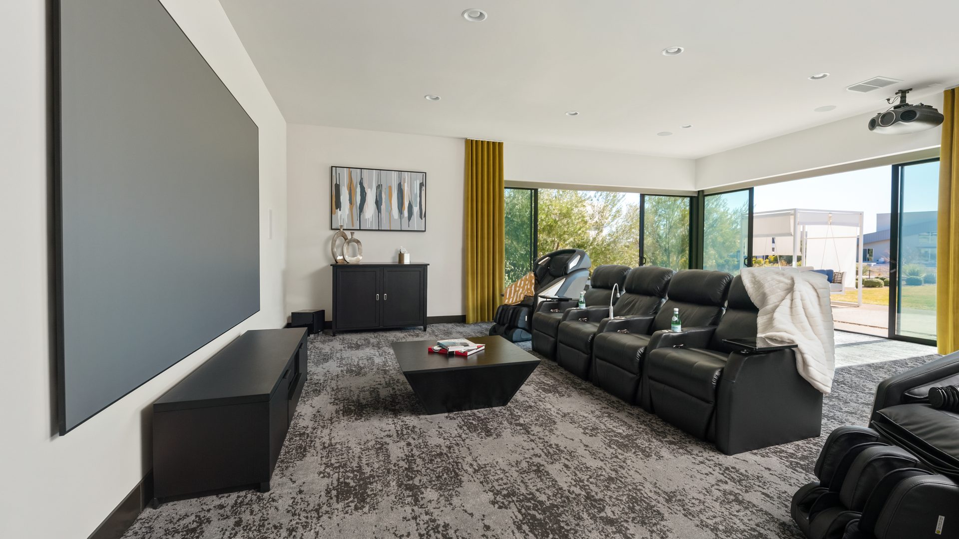 Home theater with leather recliners, gold draperies, and expansive movie screen, Reveal Interior Design Las Vegas