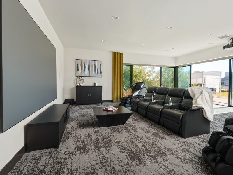 Home theater with leather recliners, gold draperies, and expansive movie screen, Reveal Interior Design Las Vegas