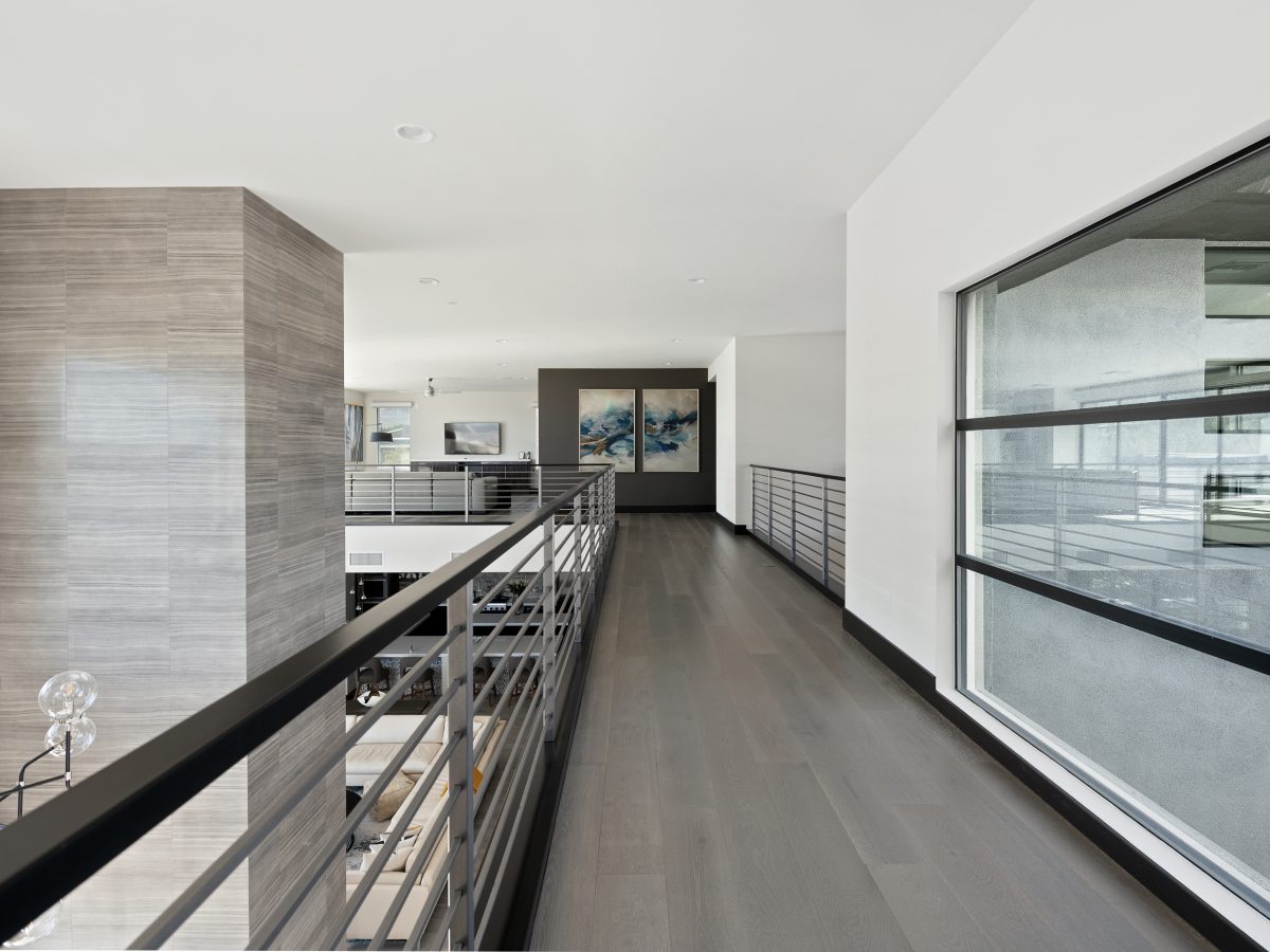Upstairs catwalk hallway with open loft seating area and patio views, Reveal Interior Design Las Vegas