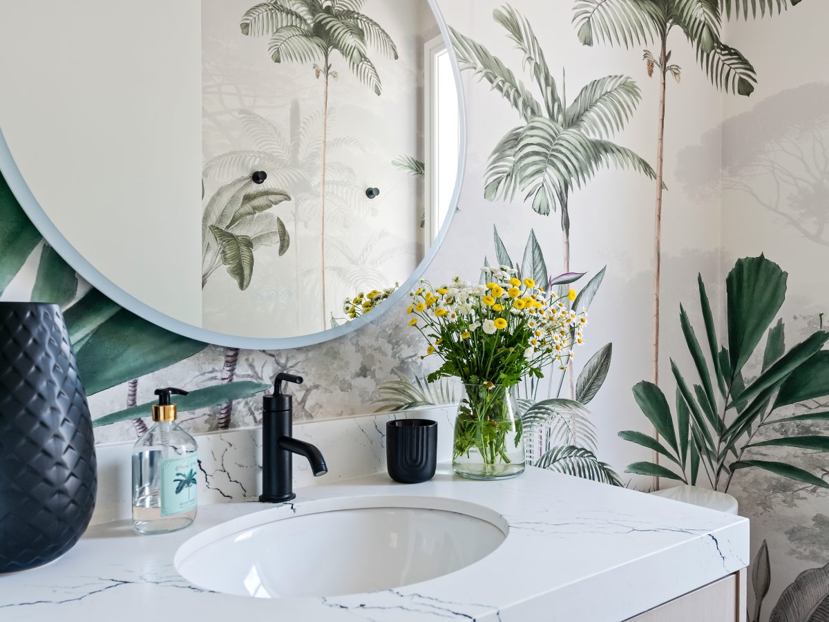 Tropical mural powder bath with white quartz vanity and round mirror, Reveal Interior Design Las Vegas