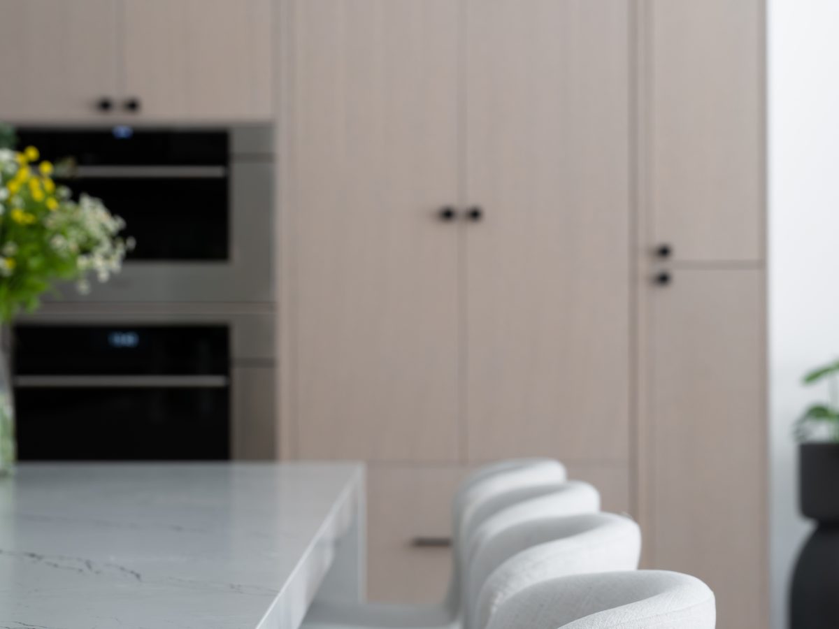 Luxury kitchen with white-washed oak cabinetry, black-veined white quartz island, and upholstered counter stools, Reveal Interior Design Las Vegas