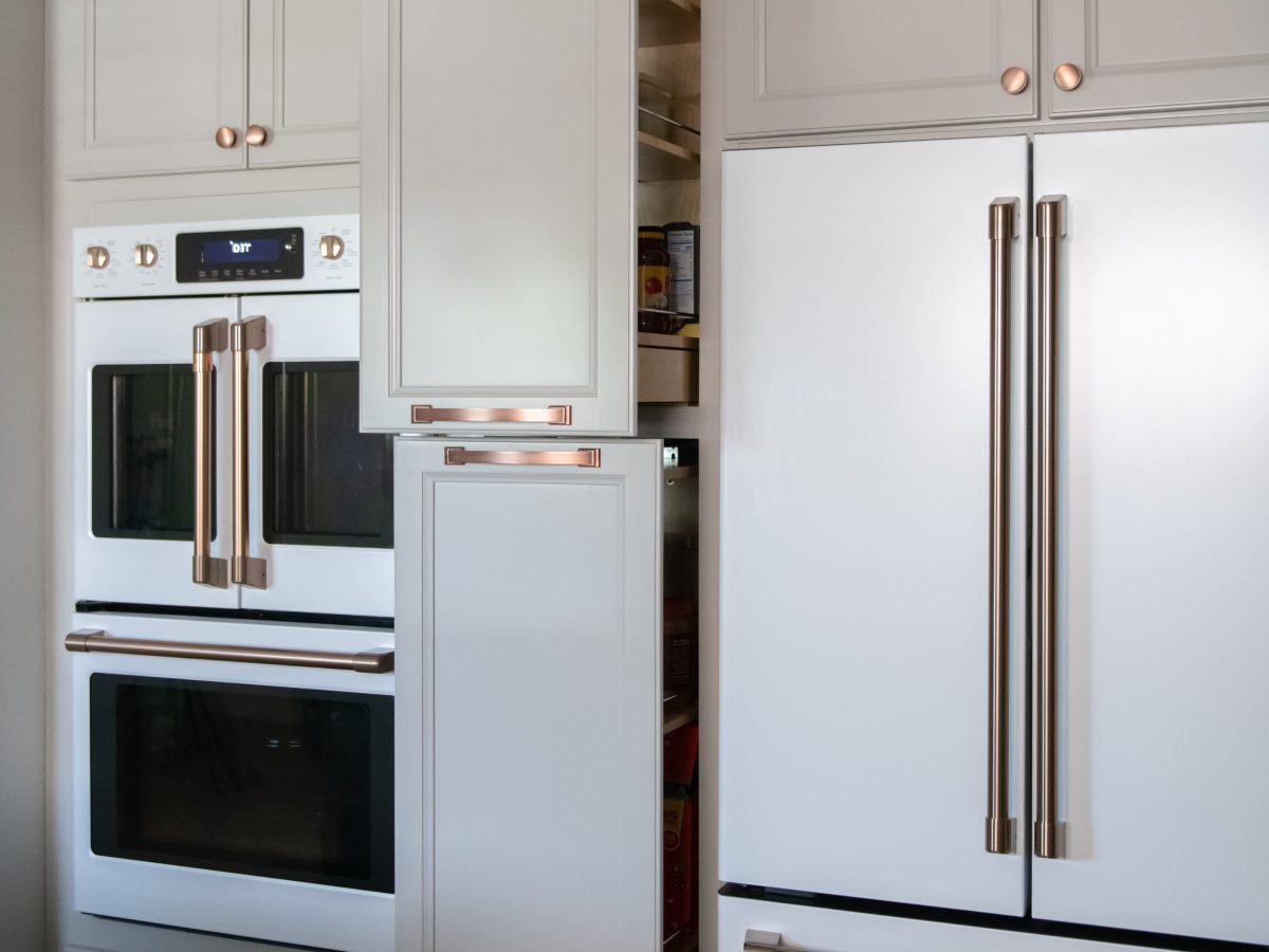 Kitchen with light beige cabinetry, copper hardware, and built-in pantry storage, Reveal Interior Design Las Vegas