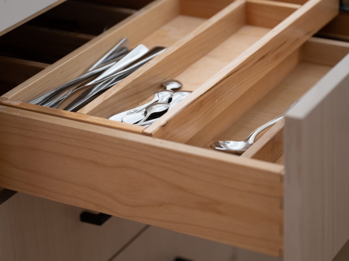 Kitchen drawer organization with warm oak cutlery insert and white quartz countertop, Reveal Interior Design Las Vegas
