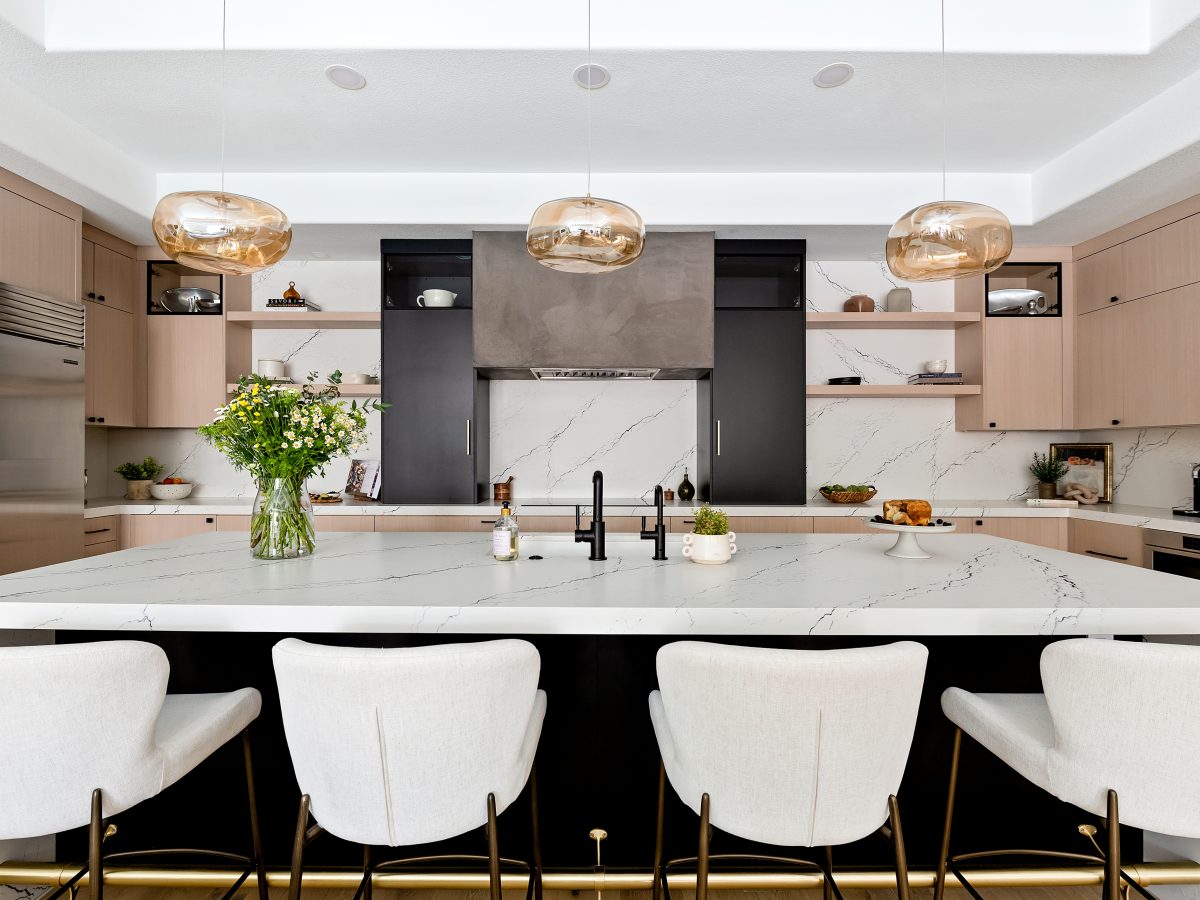 Open-concept kitchen with white-washed oak cabinetry, black quartz island, and amber pendant lighting, Reveal Interior Design Las Vegas