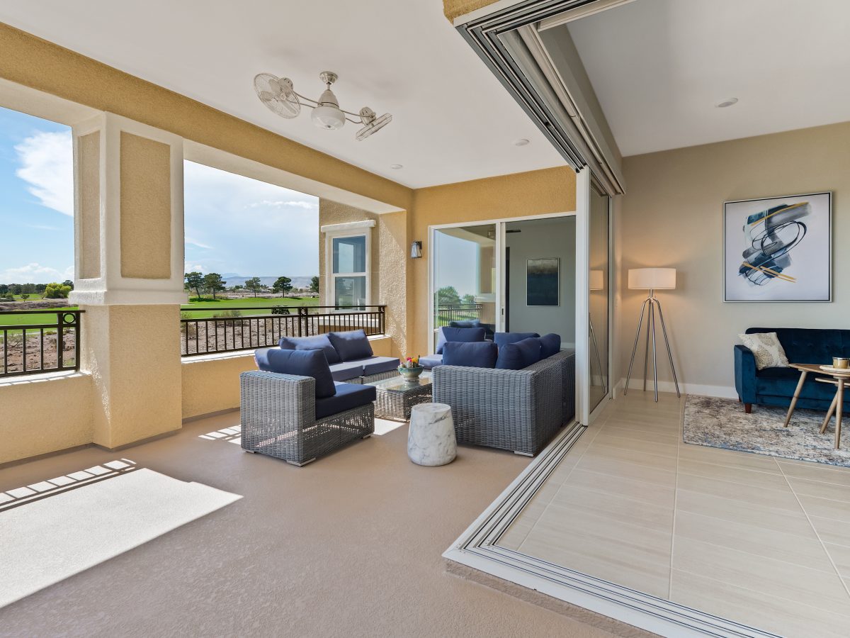 Covered outdoor patio with gray rattan seating, navy cushions, and rotating ceiling fan, Reveal Interior Design Las Vegas