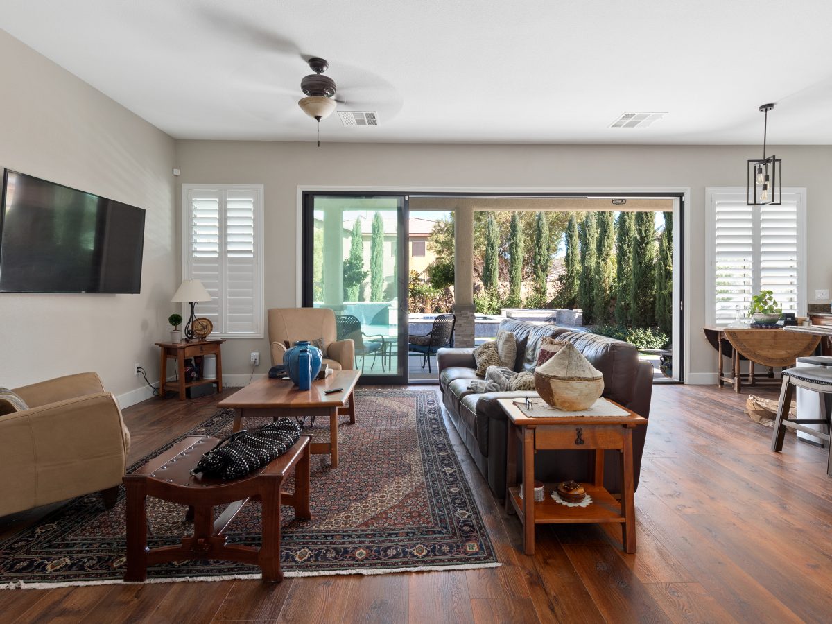 Open-concept living room with expansive black-trim sliding doors and wood flooring, Reveal Interior Design Las Vegas