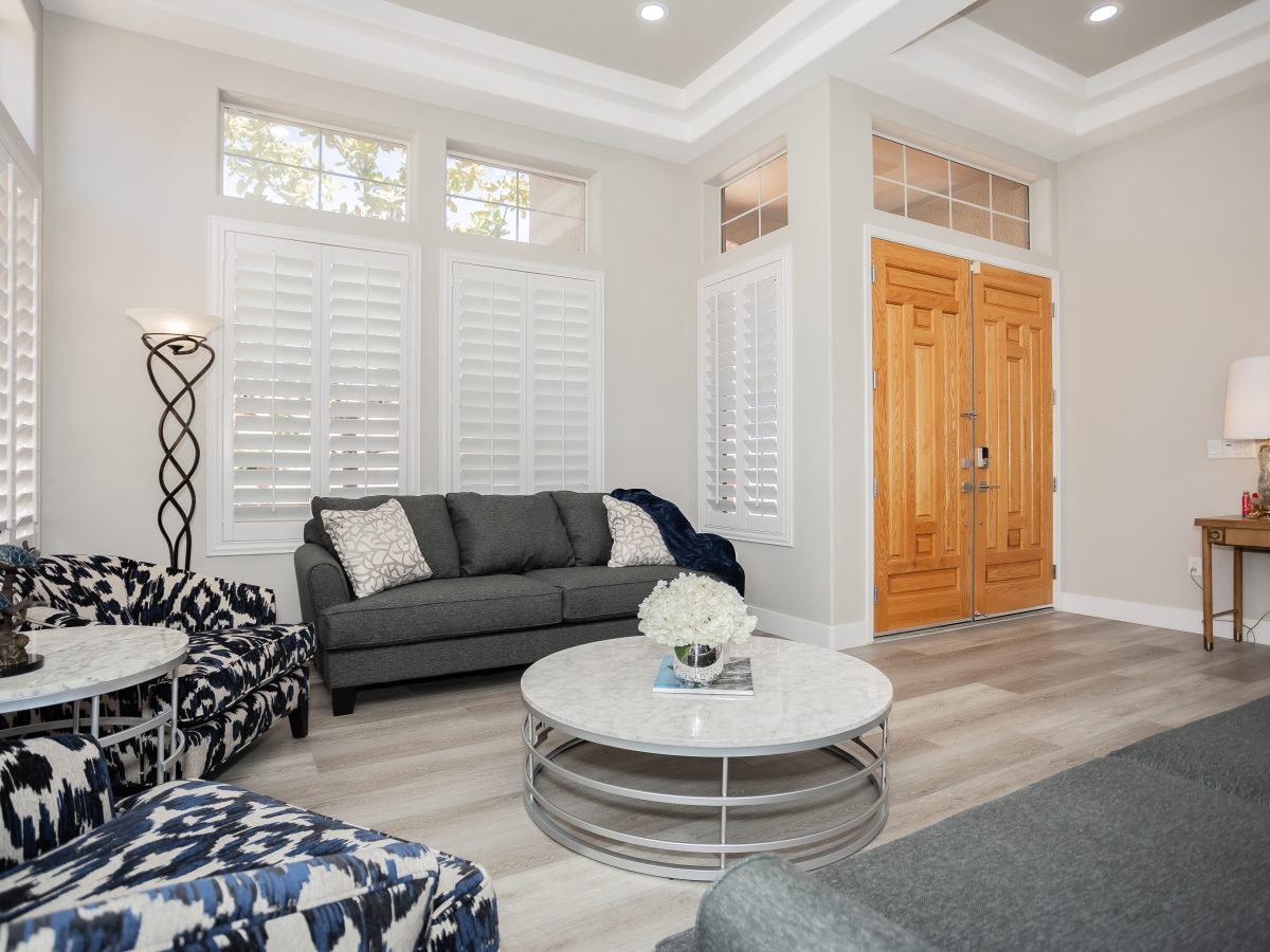 Living room with stone-look round coffee table, patterned accent chairs, and wood-look flooring, Reveal Interior Design Las Vegas