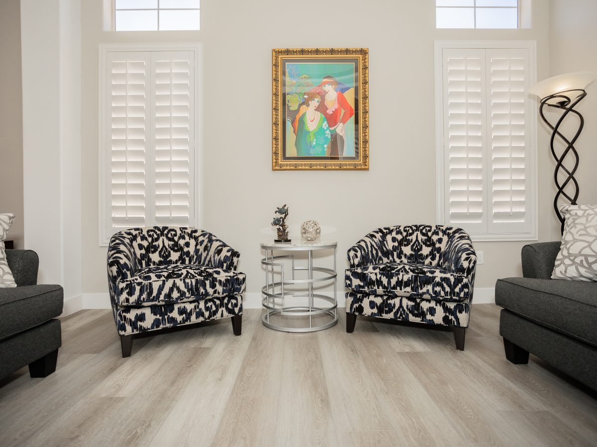Living room with patterned accent chairs, stone-look coffee table, and gray sofas, Reveal Interior Design Las Vegas