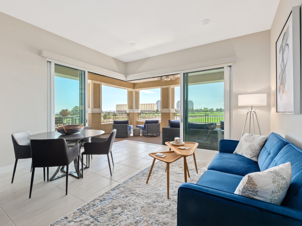 Contemporary multipurpose living and game room with blue sofa, concrete-top dining table, and balcony views, Reveal Interior Design Las Vegas