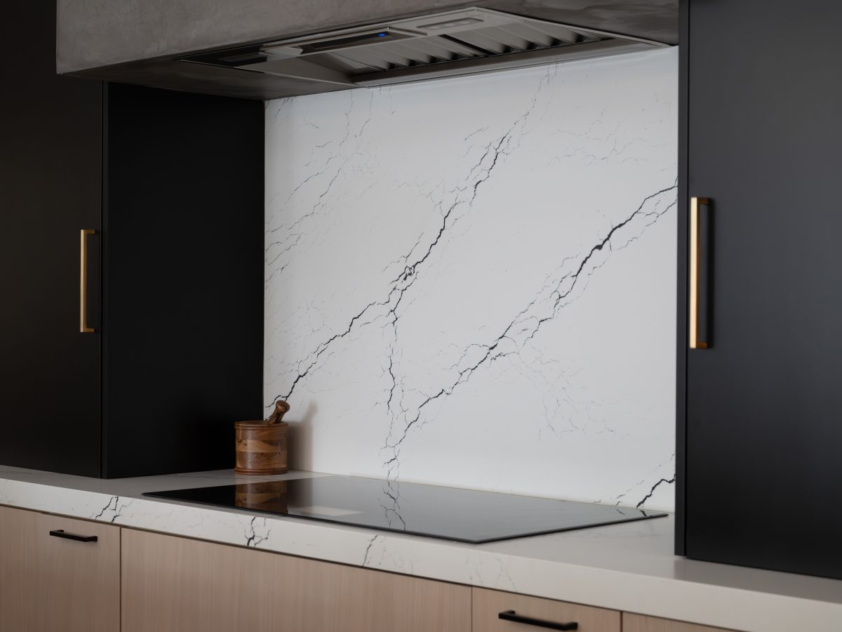 Modern kitchen with black veined white quartz backsplash, matte black upper cabinetry, and gold hardware, Reveal Interior Design Las Vegas