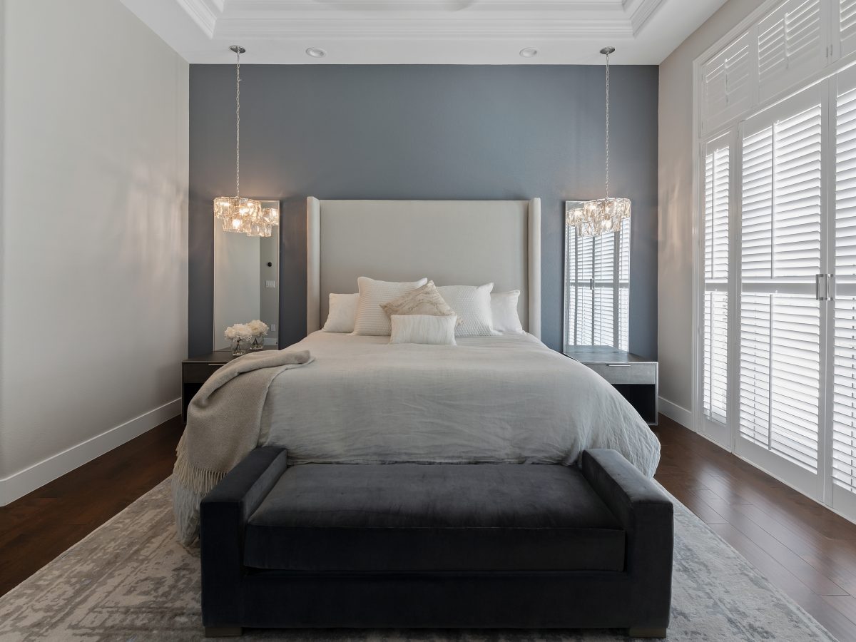Primary bedroom with slate blue accent wall, tall upholstered headboard, and pendant lighting, Reveal Interior Design Las Vegas