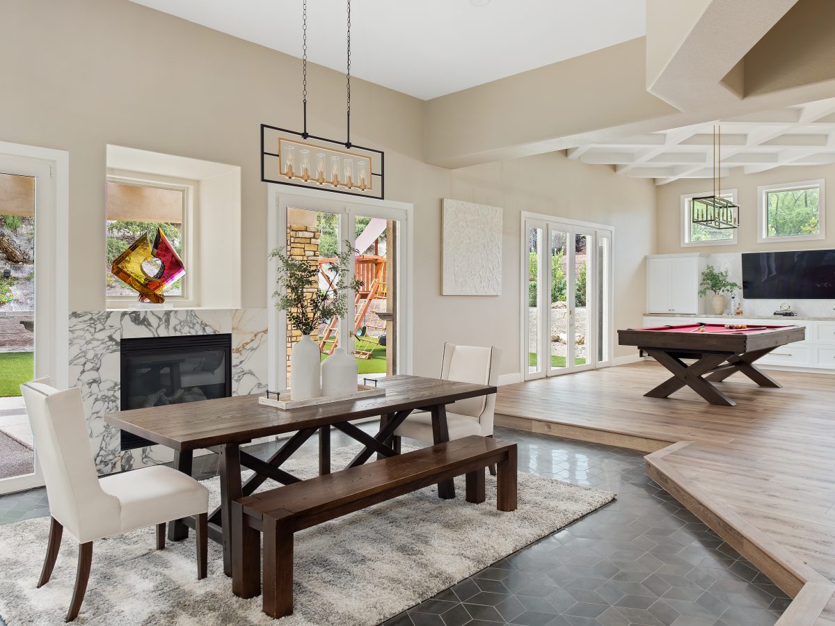 Open-concept dining room with marble fireplace surround and billiards area beyond, Reveal Interior Design Las Vegas