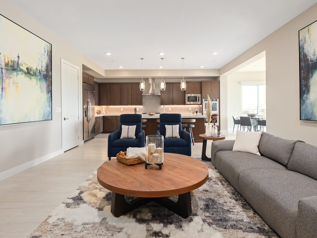 Open-concept living room with warm-stained cabinetry and white quartz kitchen, Reveal Interior Design Las Vegas
