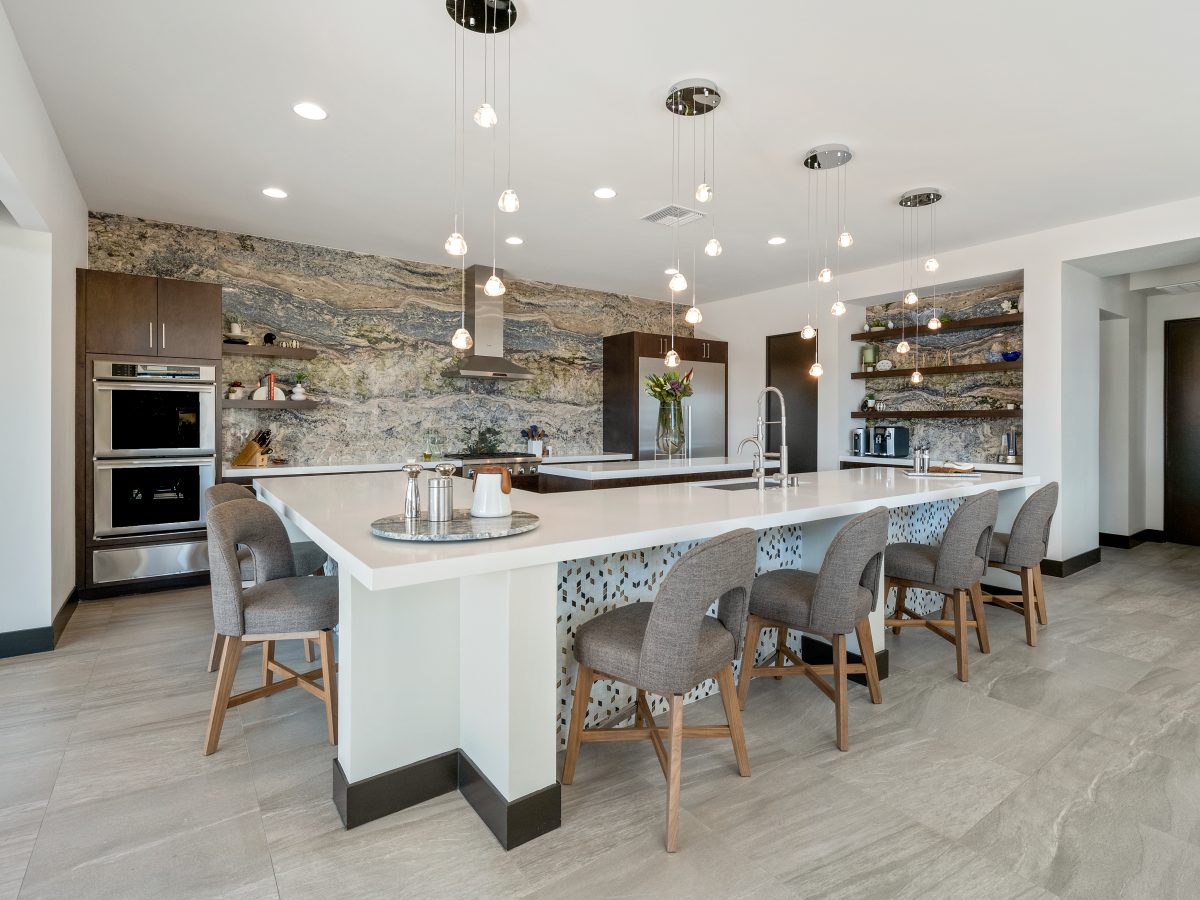 Bookmatched stone slab feature wall with white quartz island and custom bar, Reveal Interior Design Las Vegas