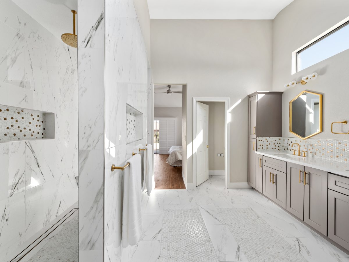 Primary bathroom with calacatta porcelain tile, taupe shaker cabinetry, and gold fixtures, Reveal Interior Design Las Vegas