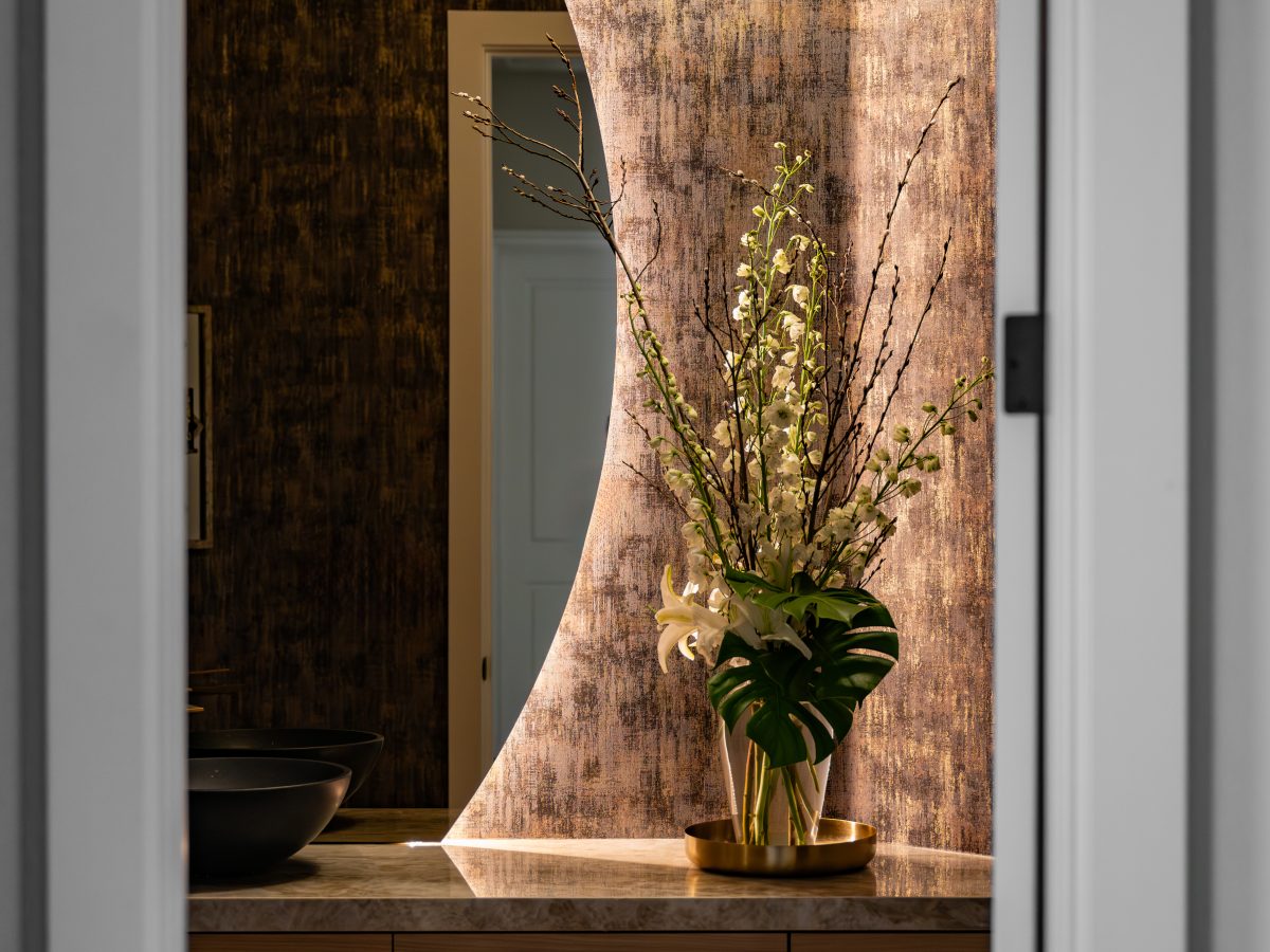 Powder bath with backlit moon mirror, Taj Mahal Dekton vanity, and metallic wallcovering, Reveal Interior Design Las Vegas